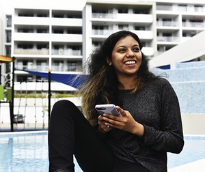 Woman on her phone by the pool at an apartment complex in Turella, South West Sydney, NSW.