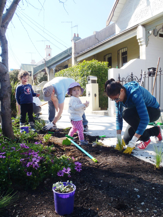 A group of people digging in soil on their street verge to create a garden.