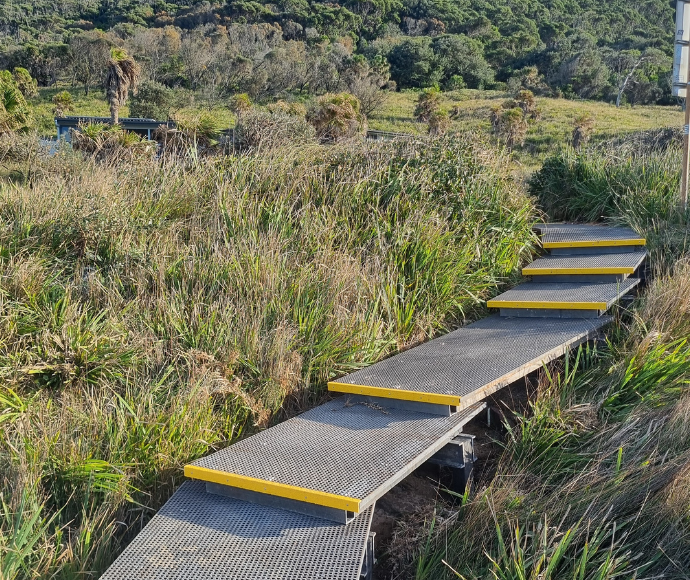 Gray ascending steps with yellow strips surrounded by green bushland