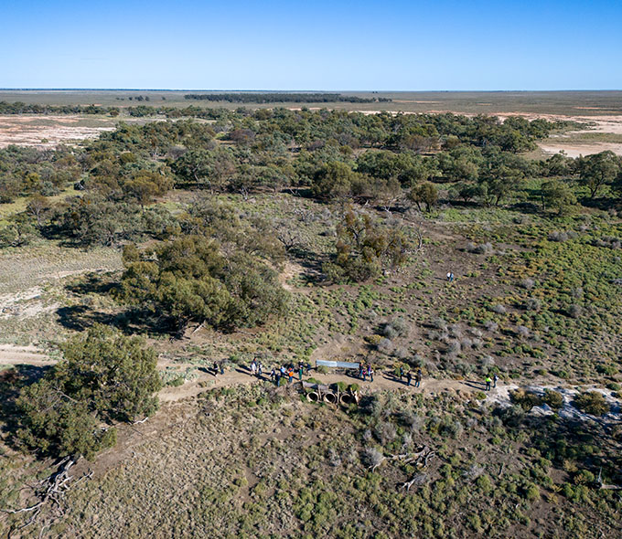 An aerial view of a landscape with green vegetation and a group of people walking along a trail