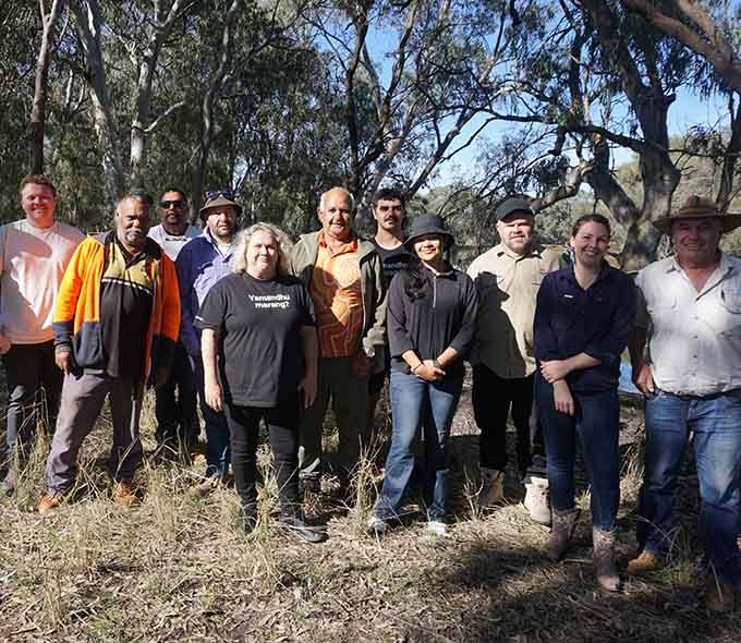 A group of workshop participants stand in front of a cleared area