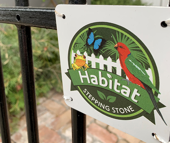 Habitat Stepping Stones plaque attached to black wrought iron fence.